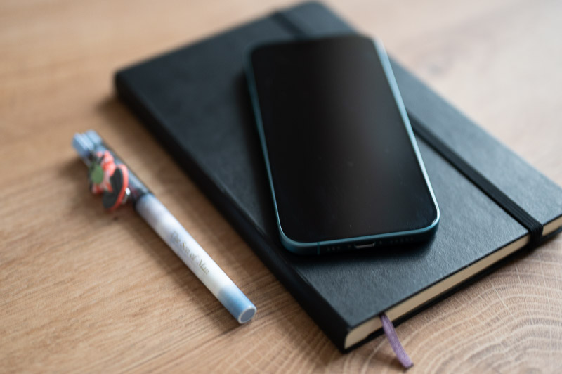 Ein Mobiltelefon liegt auf einem Notizbuch neben einem Stift